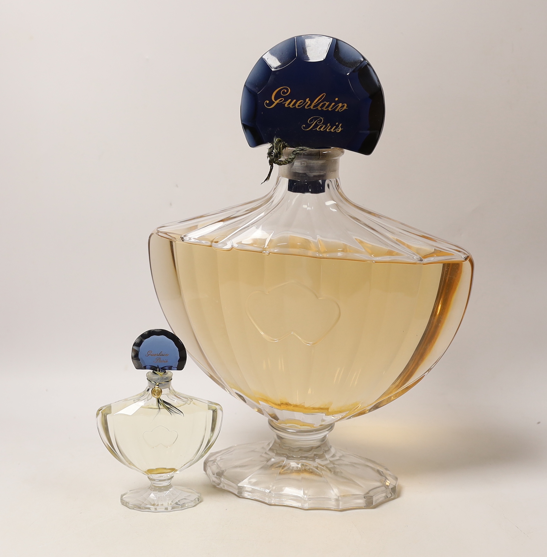 A large Guerlain Paris advertising perfume bottle and a similar smaller bottle, tallest 37cm